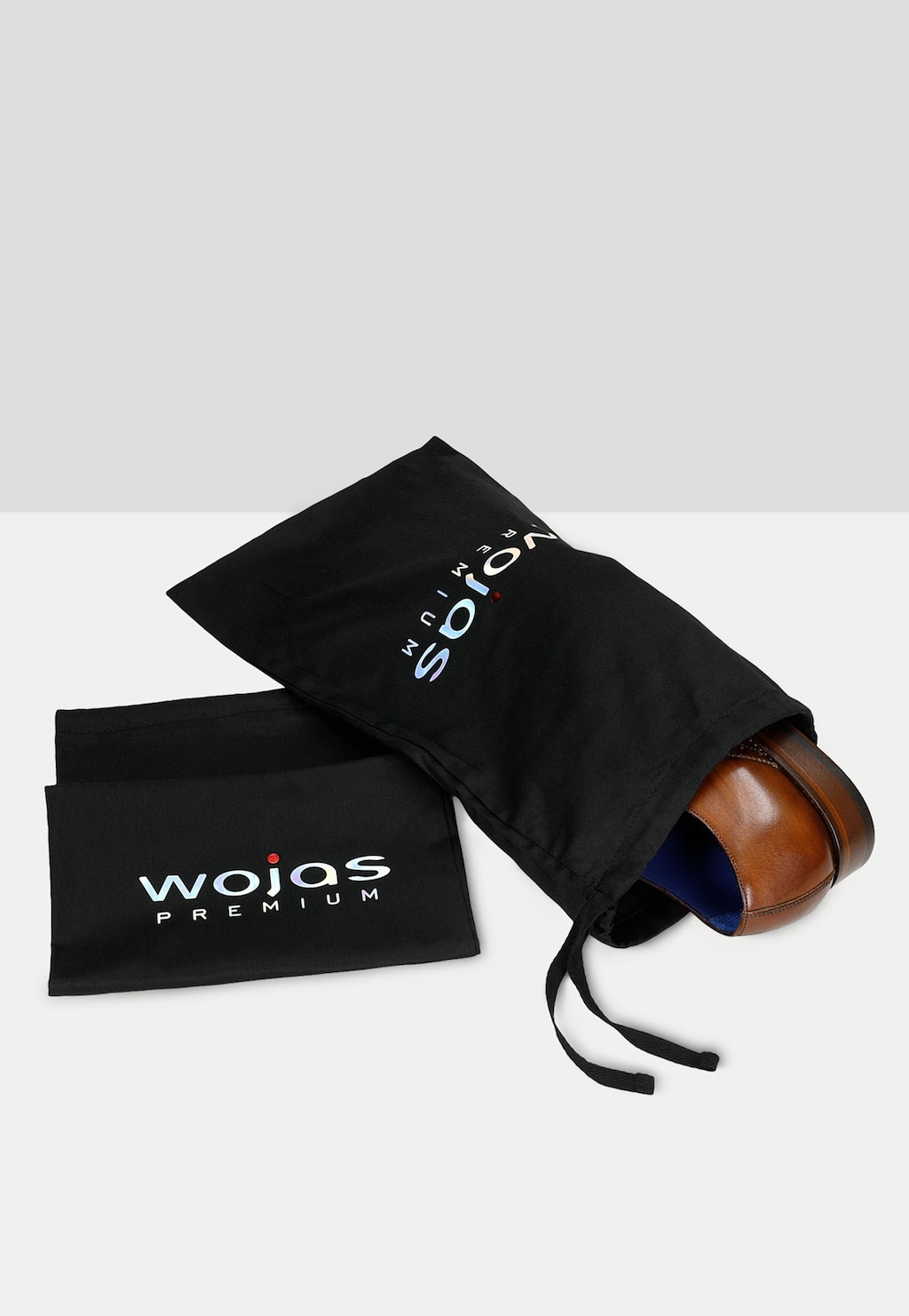 Eleganckie oxfordy Wojas PREMIUM 10061-52 w jasnobrązowym kolorze wystające z czarnego woreczka ochronnego z logo marki, obok leży etykieta produktu.