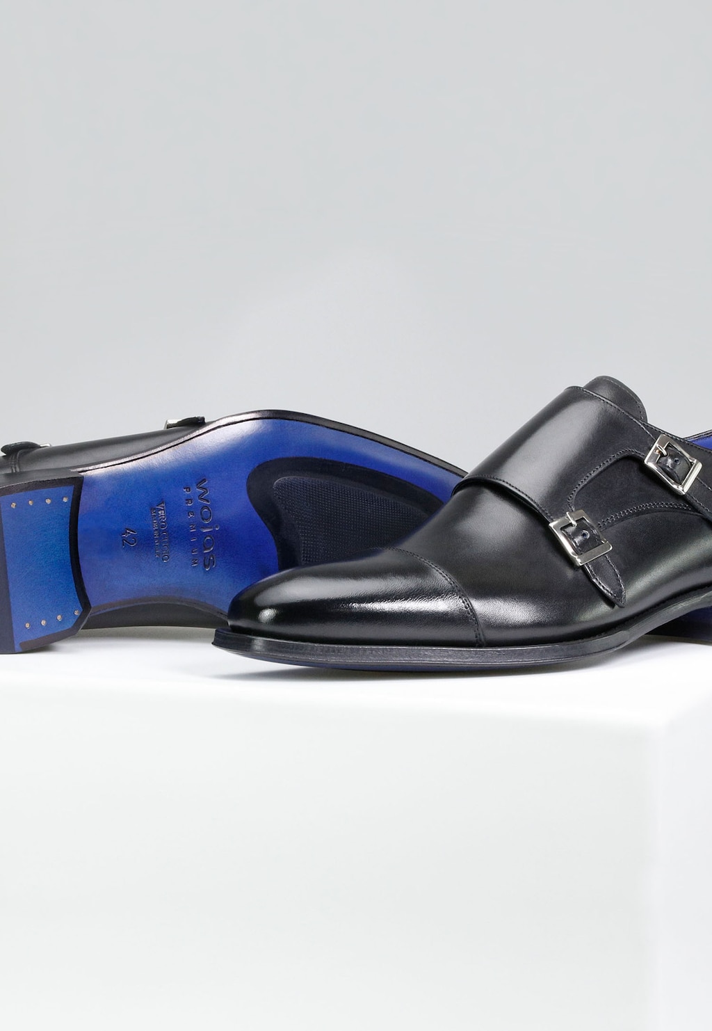 Eleganckie czarne buty monki Wojas PREMIUM model 10059-51 z dwiema metalowymi klamrami, widoczna charakterystyczna niebieska podeszwa z logo marki.