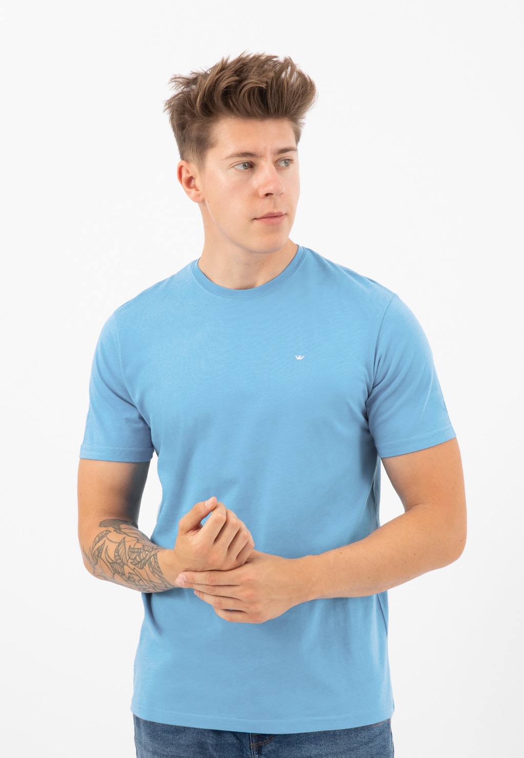 Jasnoniebieski t-shirt męski Wojas model 98018-88 z bawełny, z okrągłym dekoltem i krótkim rękawem, prezentowany na modelu z tatuażem na przedramieniu.