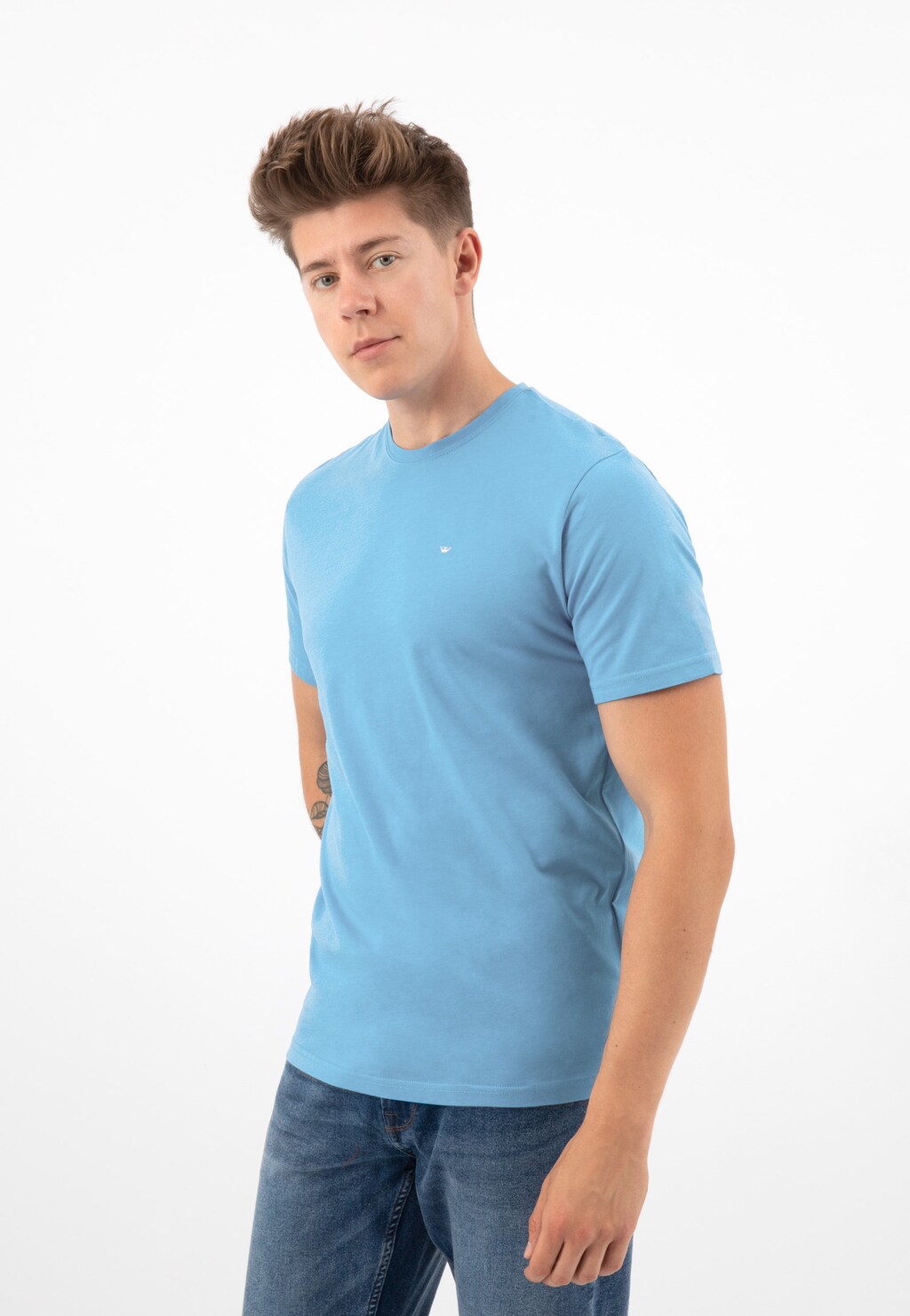 Jasnoniebieski t-shirt męski Wojas model 98018-88 z bawełny, prezentowany przez modela z uniesioną fryzurą, widok z przodu, z małym logo na piersi.