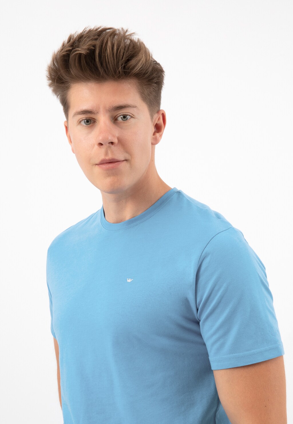 Jasnoniebieski t-shirt męski Wojas model 98018-88 prezentowany na modelu. Bawełniana koszulka z krótkim rękawem i okrągłym dekoltem, z małym logo.