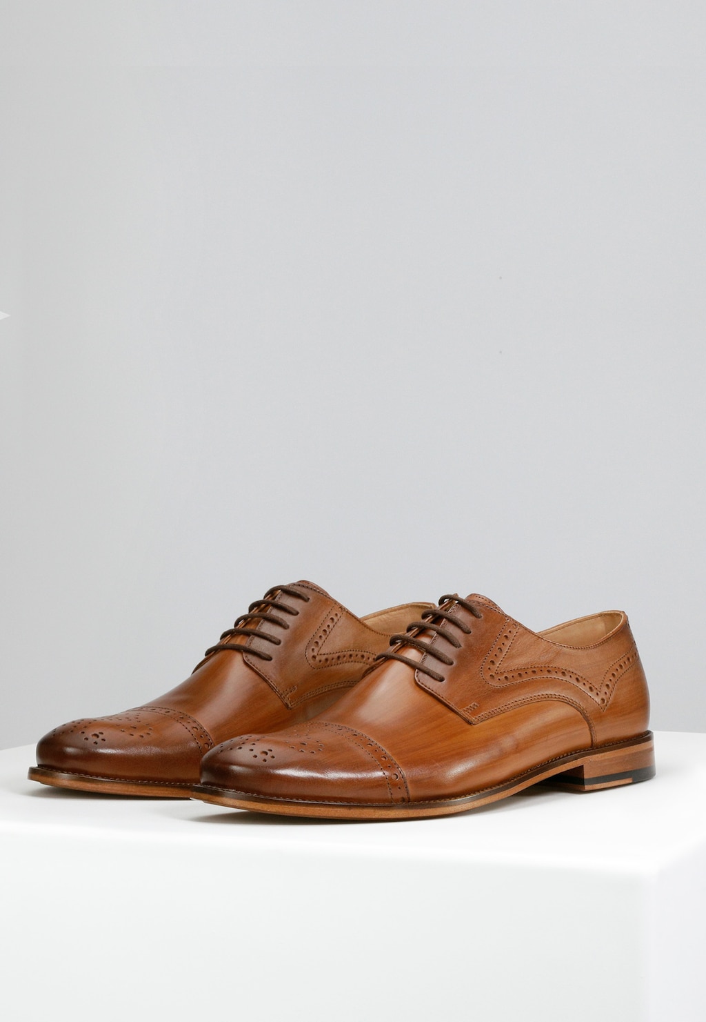 Eleganckie jasnobrązowe półbuty męskie Wojas model 10054-53 z kolekcji PREMIUM. Skórzane buty z ozdobną perforacją na czubku, sznurowane, z widocznym drewnianym obcasem.