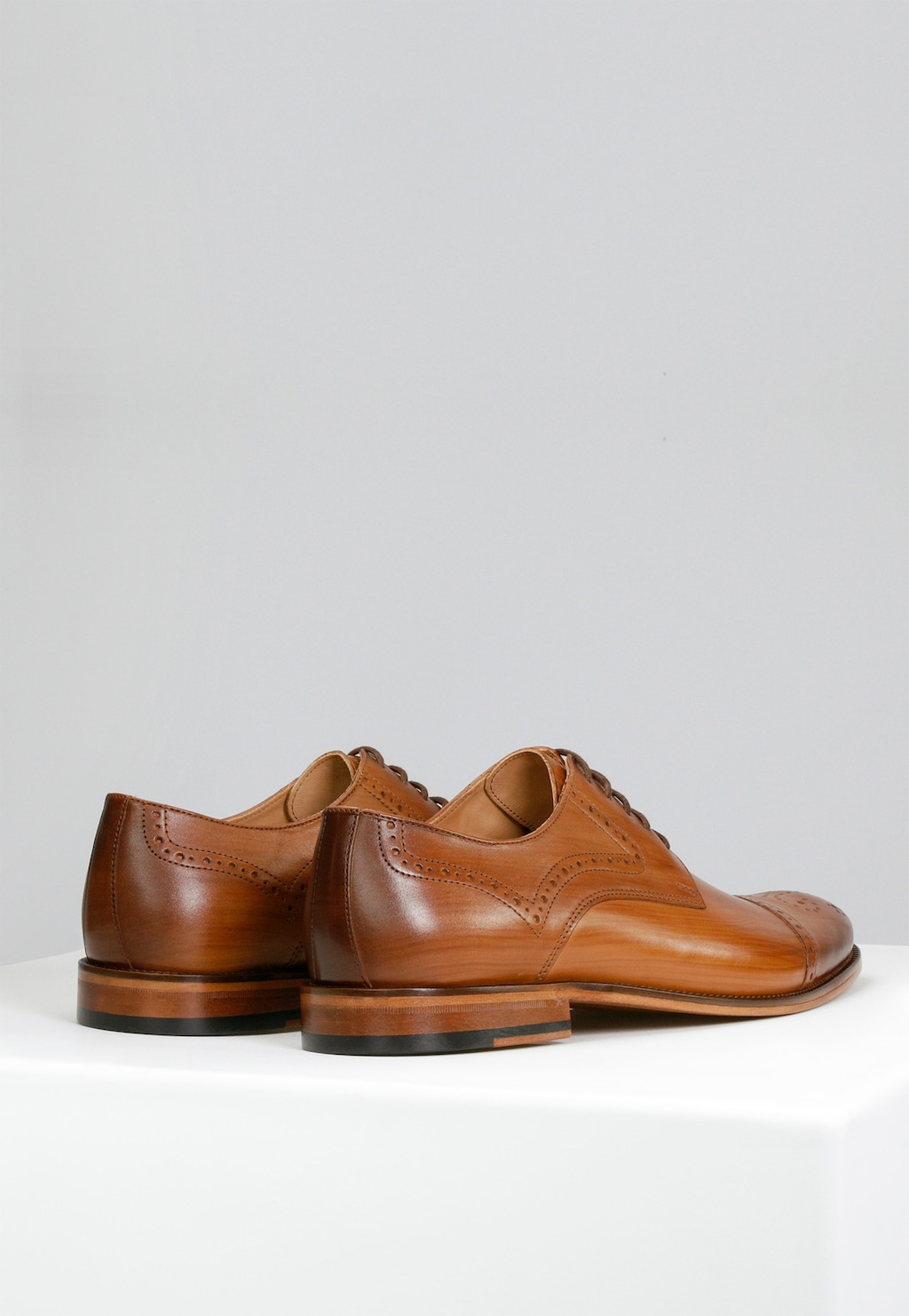 Eleganckie jasnobrązowe półbuty Wojas PREMIUM 10054-53 widoczne z tyłu, wykonane z wysokiej jakości skóry, ozdobione klasycznym ażurowym zdobieniem i drewnianą podeszwą.