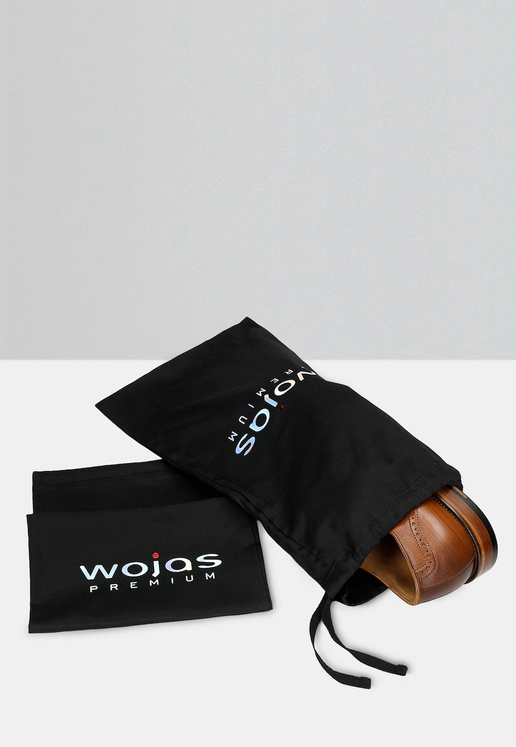 Jasnobrązowe wizytowe półbuty męskie Wojas PREMIUM model 10054-53 w czarnym woreczku ochronnym z logo marki, widoczny fragment eleganckich butów.