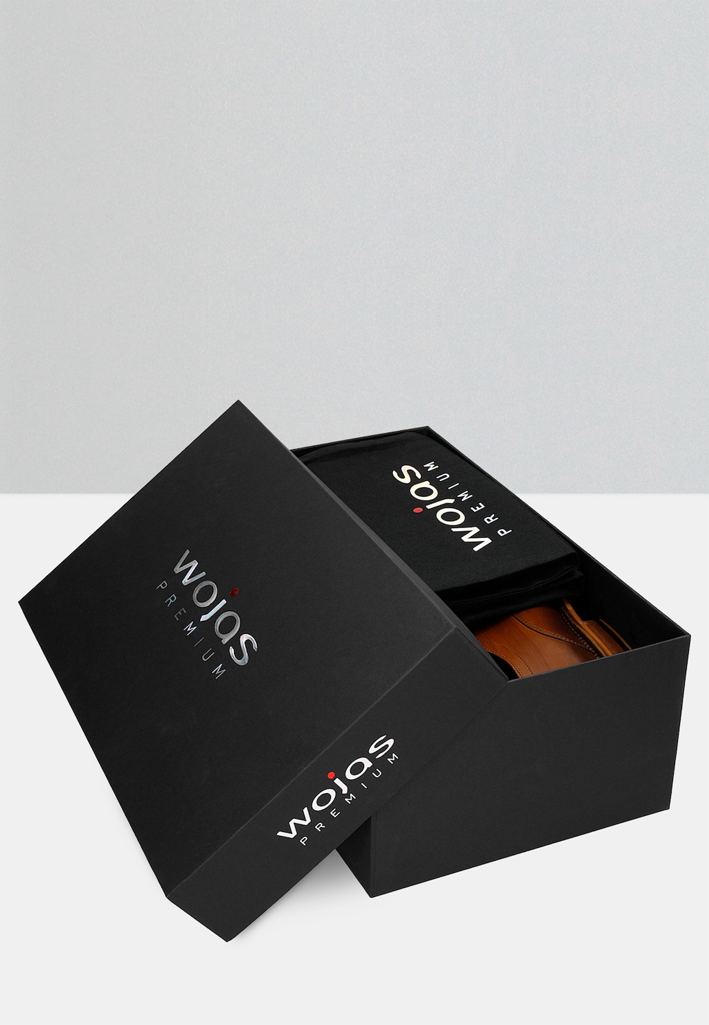 Eleganckie czarne pudełko Wojas Premium z uchyloną pokrywą, ukazujące brązowe półbuty męskie wizytowe model 10053-53 ze skórzaną podeszwą.