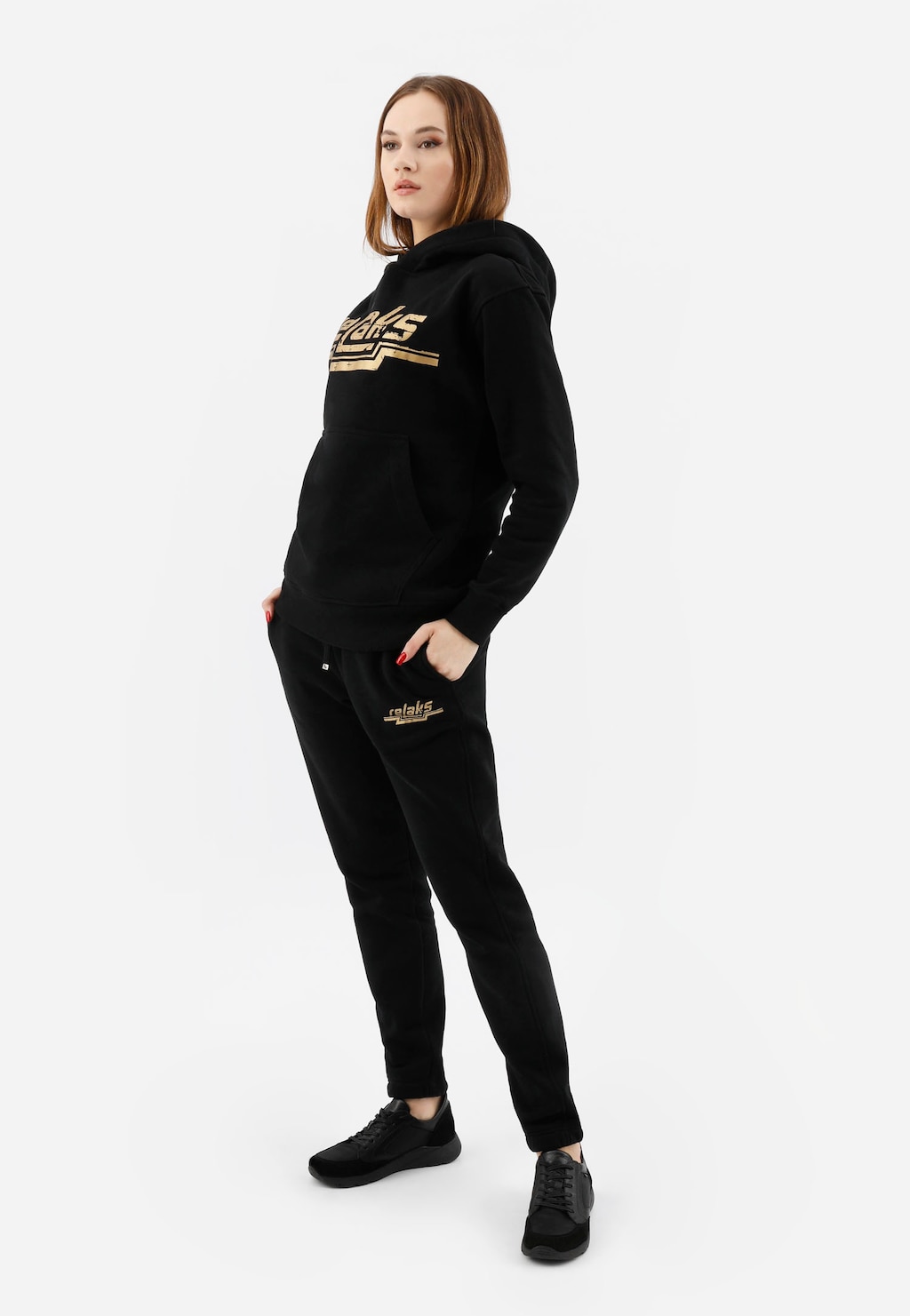 Czarna bluza damska RELAKS model 98023-81 z kapturem i złotym logo, prezentowana w komplecie ze spodniami tej samej marki i czarnymi sportowymi butami.