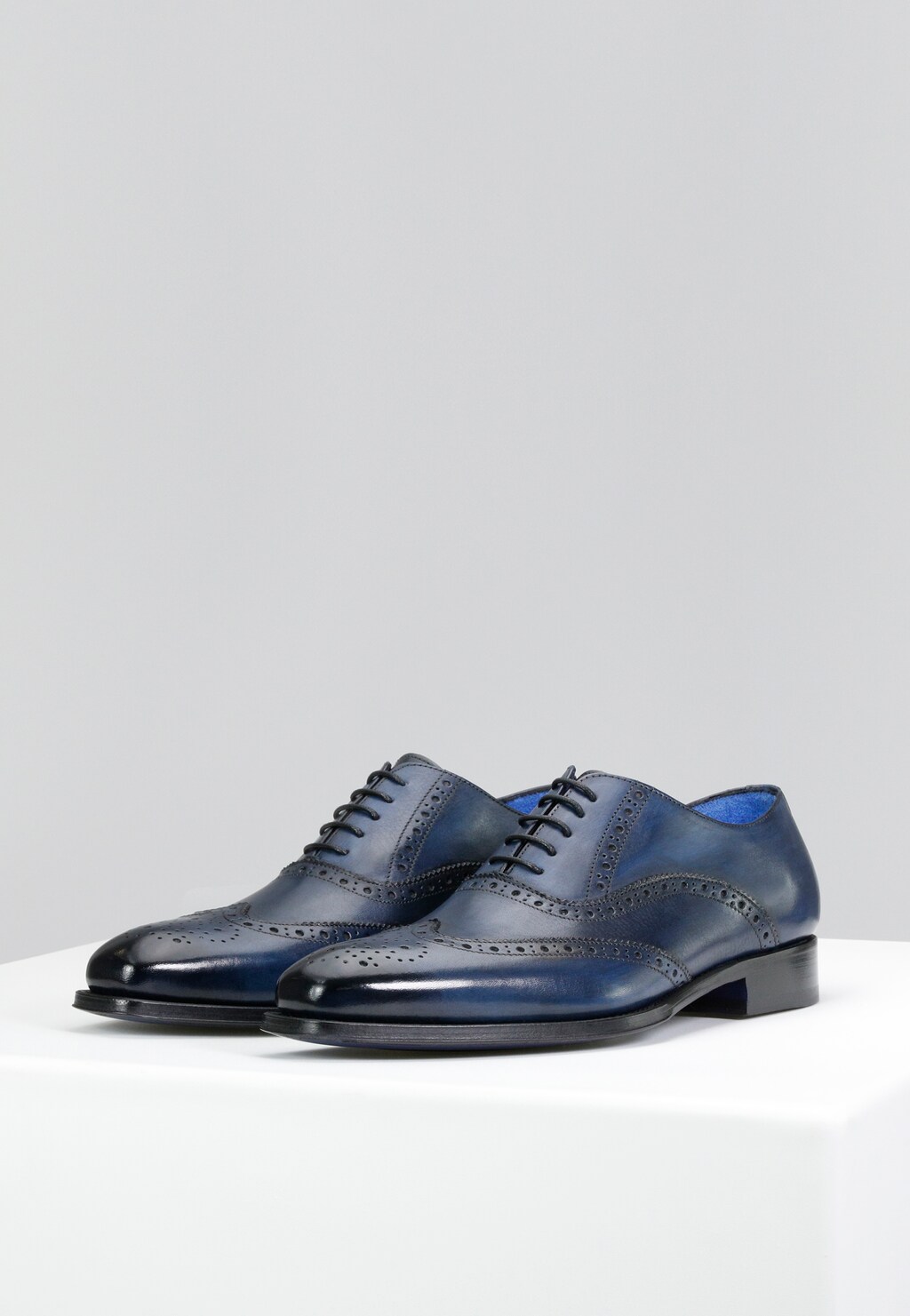 Eleganckie granatowe półbuty męskie Wojas PREMIUM 10060-56 w stylu oxford z ozdobną perforacją brogues, widocznym niebieskim wykończeniem wnętrza i klasycznym sznurowaniem.