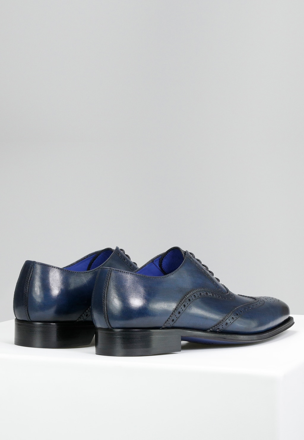 Eleganckie granatowe półbuty męskie Wojas PREMIUM 10060-56 w stylu oxford z ozdobnymi perforacjami, czarnymi podeszwami i niebieskim wykończeniem wnętrza.