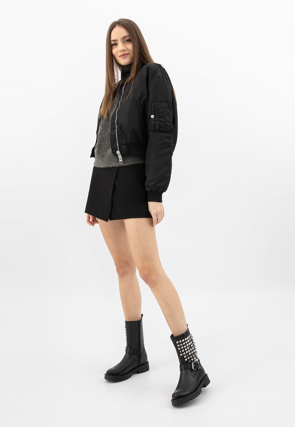 Modelka w czarnej stylizacji prezentująca czarne skórzane bikery damskie Wojas model 55250-51 z charakterystycznymi ćwiekami na cholewce, widoczne z perspektywy całej sylwetki.