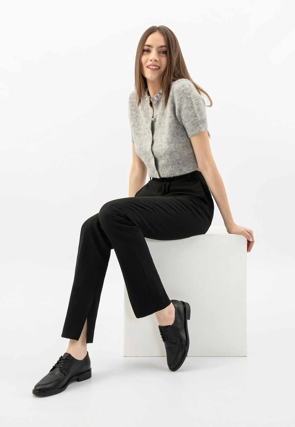 Osoba w szarym sweterku i czarnych spodniach prezentująca czarne eleganckie półbuty Wojas model 46250-51 ze sznurowaniem, idealne do stylizacji biznesowych.