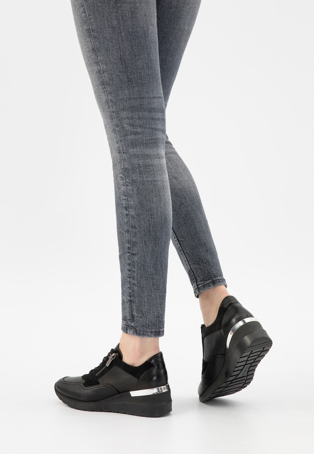 Czarne sneakersy damskie Wojas model 46091-71 z ozdobnym zamkiem, prezentowane na nogach w szarych jeansach. Widok z tyłu ukazuje srebrne detale na podeszwie.