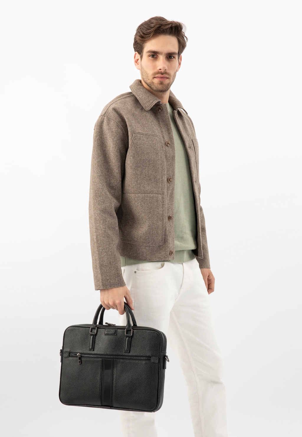 Elegancka czarna skórzana torba męska Wojas model 90014-51 z dodatkową kieszonką na zamek, trzymana w dłoni, dopełniająca stylizację z wełnianą kurtką i jasnymi spodniami.