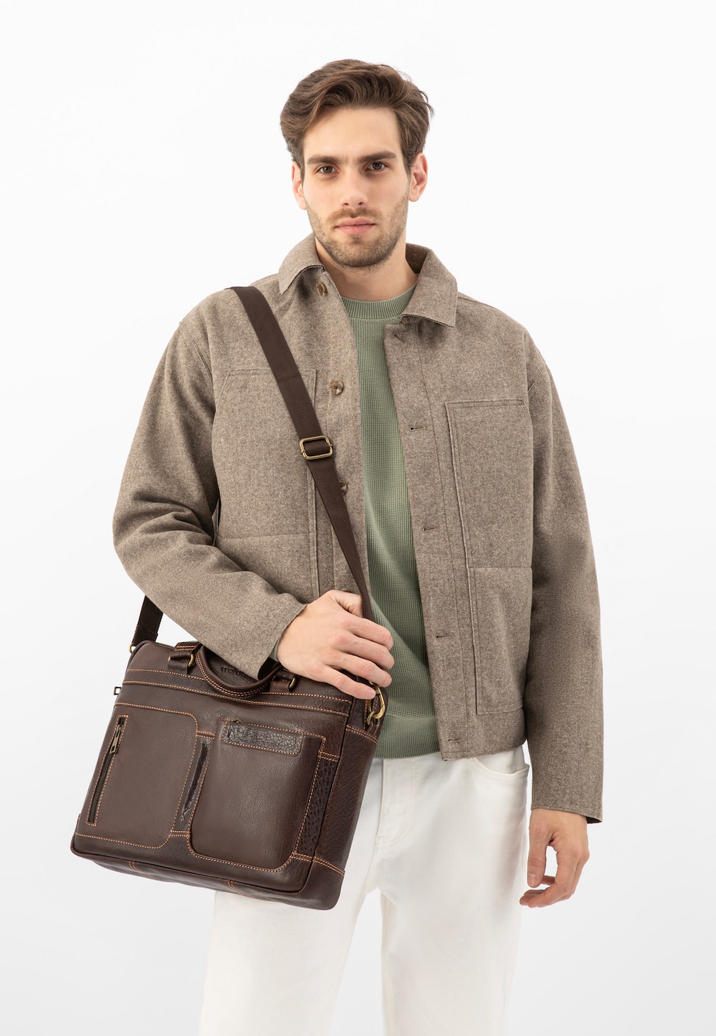 Model prezentujący brązową skórzaną torbę męską Wojas 80141-52 na ramieniu, ubrany w beżową kurtkę i zielony sweter. Elegancka torba biznesowa z przegródkami i rączkami.