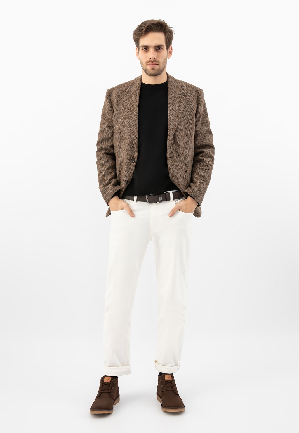 Model ubrany w elegancki strój z brązowymi trzewikiami Wojas 24400-63 typu desert boots wykonanymi z dwoiny welurowej, doskonale uzupełniającymi stylizację z marynarką i białymi spodniami.