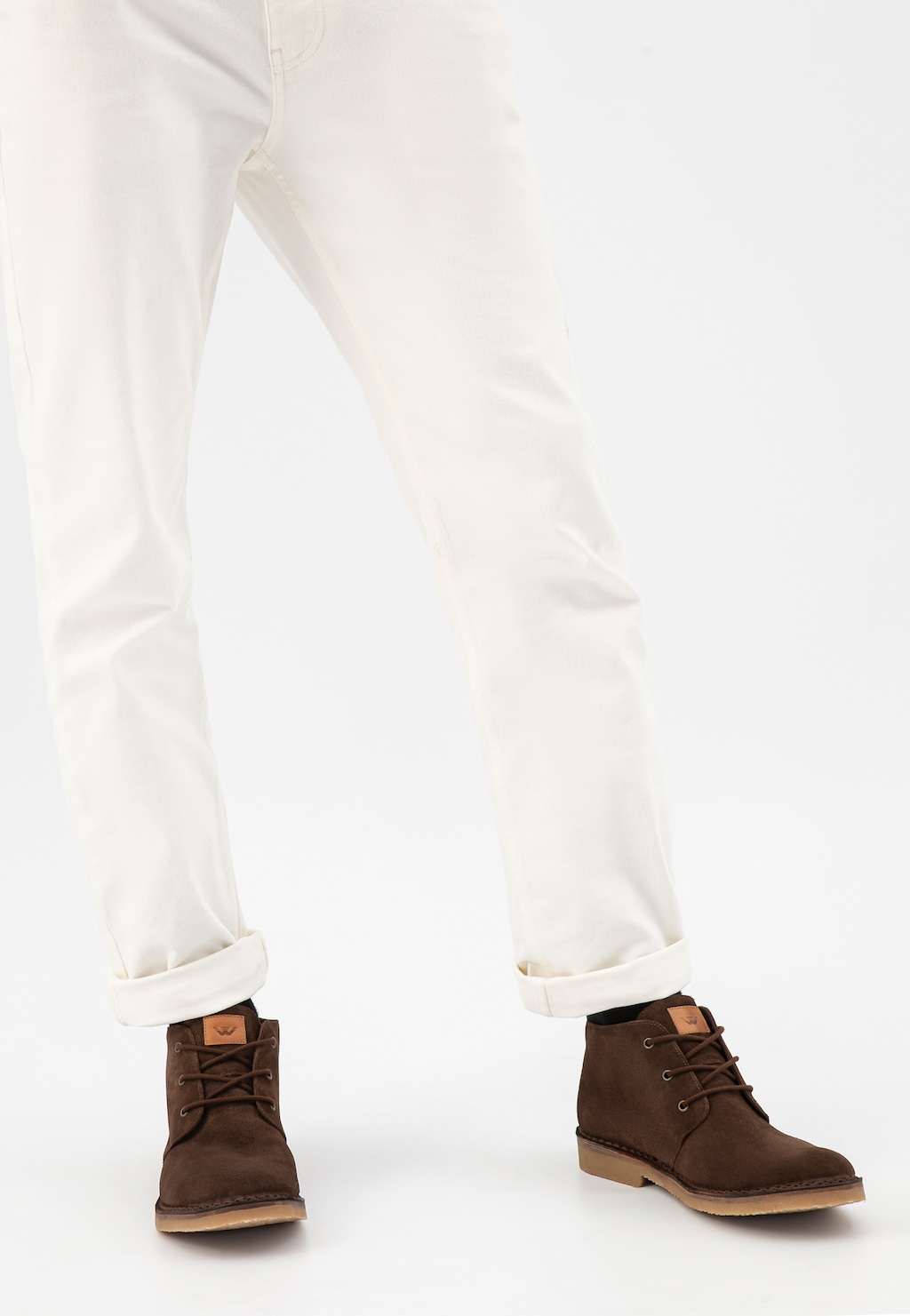 Brązowe trzewiki męskie Wojas model 24400-63 typu desert boots wykonane z dwoiny welurowej, noszone do białych spodni z podwiniętymi nogawkami.