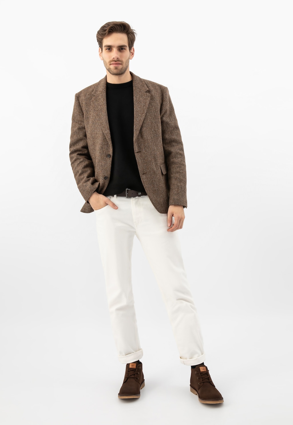 Model w eleganckim stroju prezentujący brązowe trzewiki męskie Wojas 24400-63 typu desert boots z dwoiny welurowej, widoczne na nogach w połączeniu z białymi spodniami i brązową marynarką.
