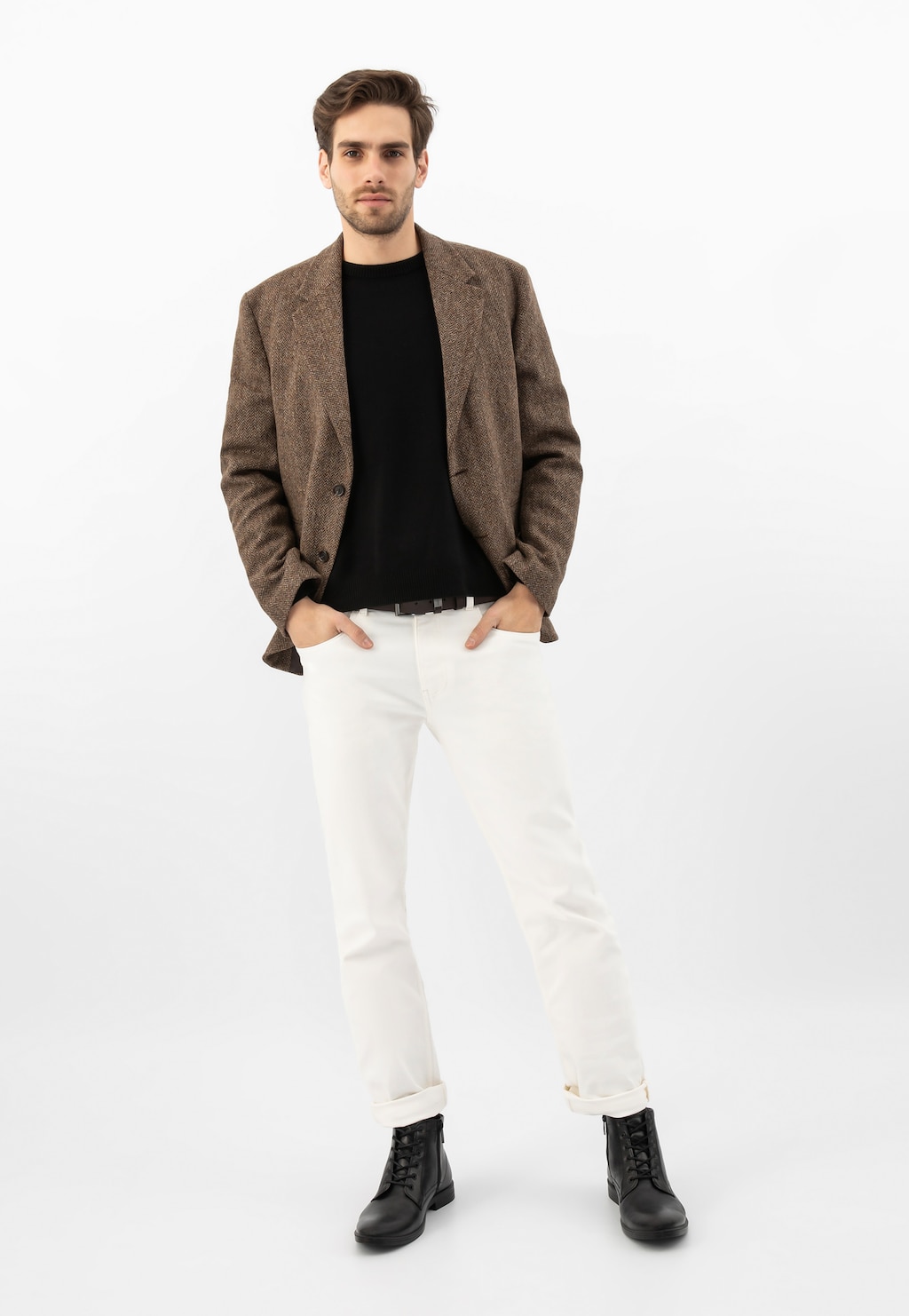 Model prezentujący czarne eleganckie trzewiki męskie Wojas 24055-51 ze skóry licowej, ubrany w brązową marynarkę, czarny sweter i białe spodnie.