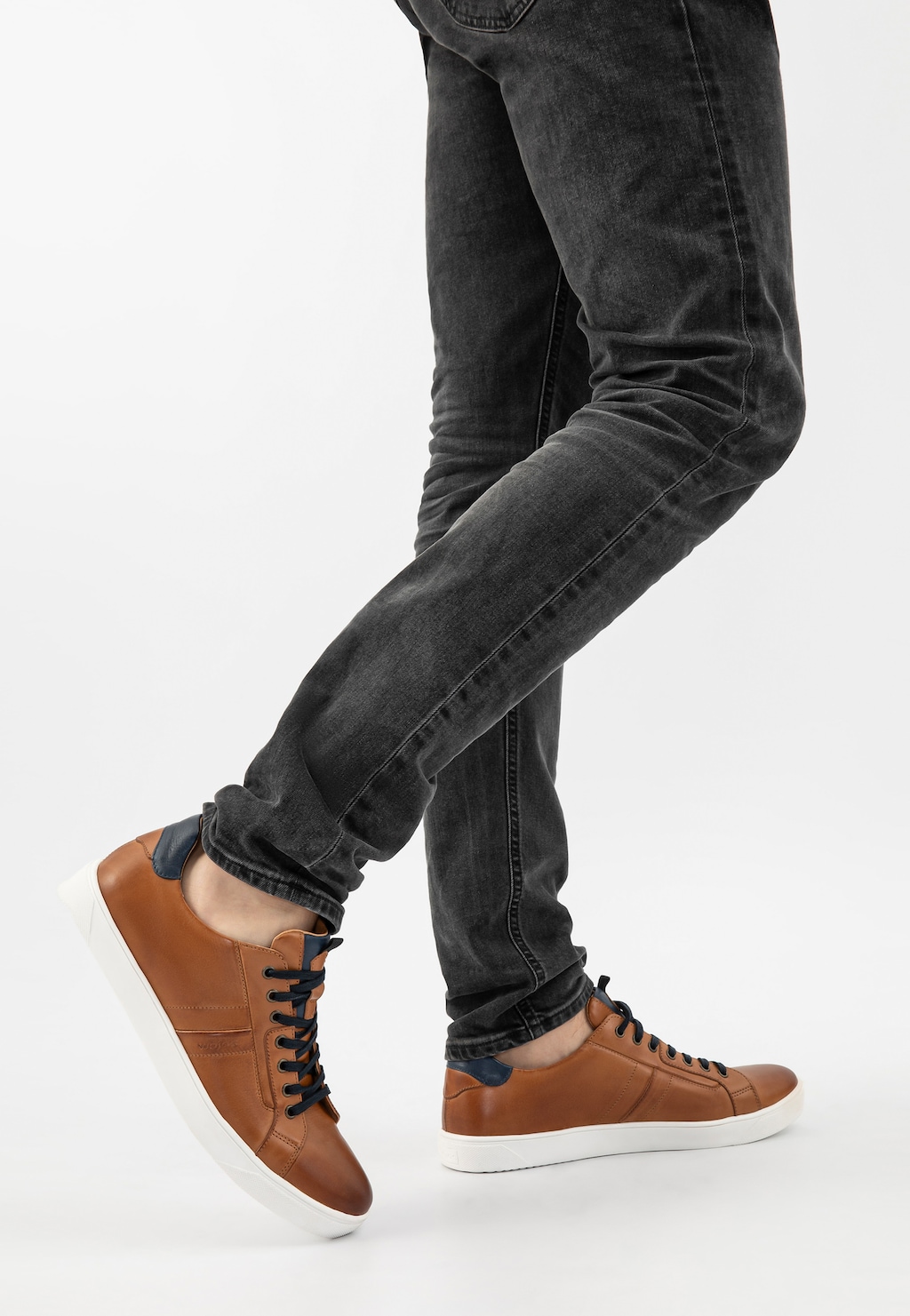 Jasnobrązowe trampki Wojas model 10167-52 z granatowymi wstawkami, prezentowane na nogach osoby w ciemnych jeansach, z białą podeszwą, pokazane z profilu.