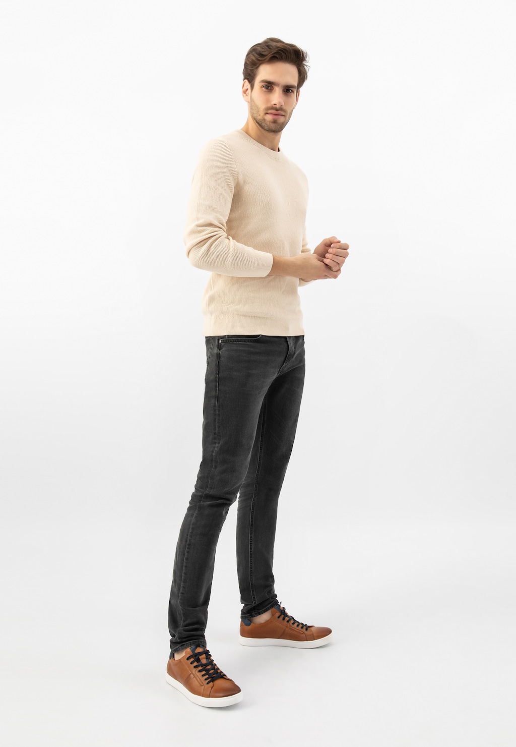 Model w jasnobeżowym swetrze i czarnych jeansach prezentuje jasnobrązowe trampki Wojas 10167-52 z granatowymi wstawkami i czarnymi sznurówkami na białej podeszwie.