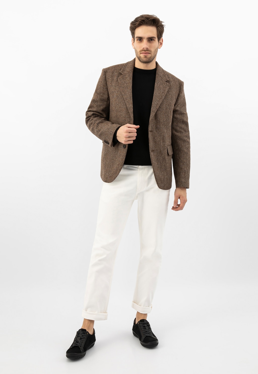 Model w eleganckim stroju z brązową marynarką, czarnym t-shirtem i białymi spodniami, prezentujący czarne sneakersy Wojas model 10147-71 na oryginalnej podeszwie.