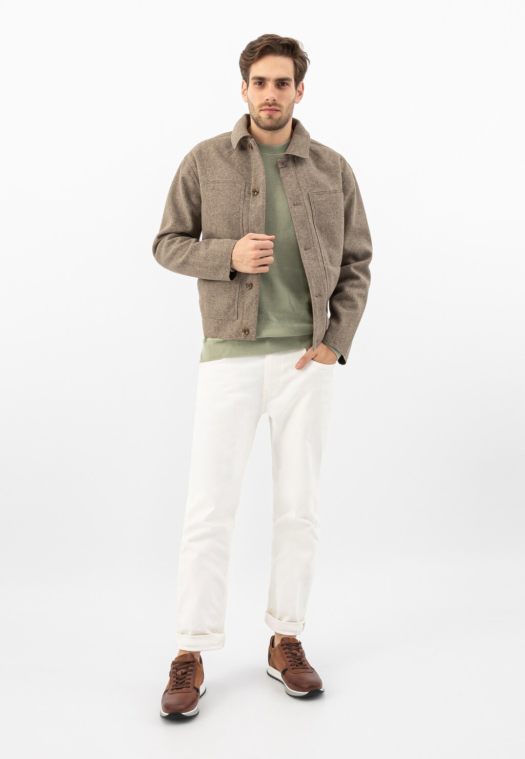 Model w stylizacji casualowej prezentuje jasnobrązowe sneakersy Wojas 10021-73 z czarnymi detalami, nosi beżową kurtkę, zieloną koszulkę i białe spodnie.