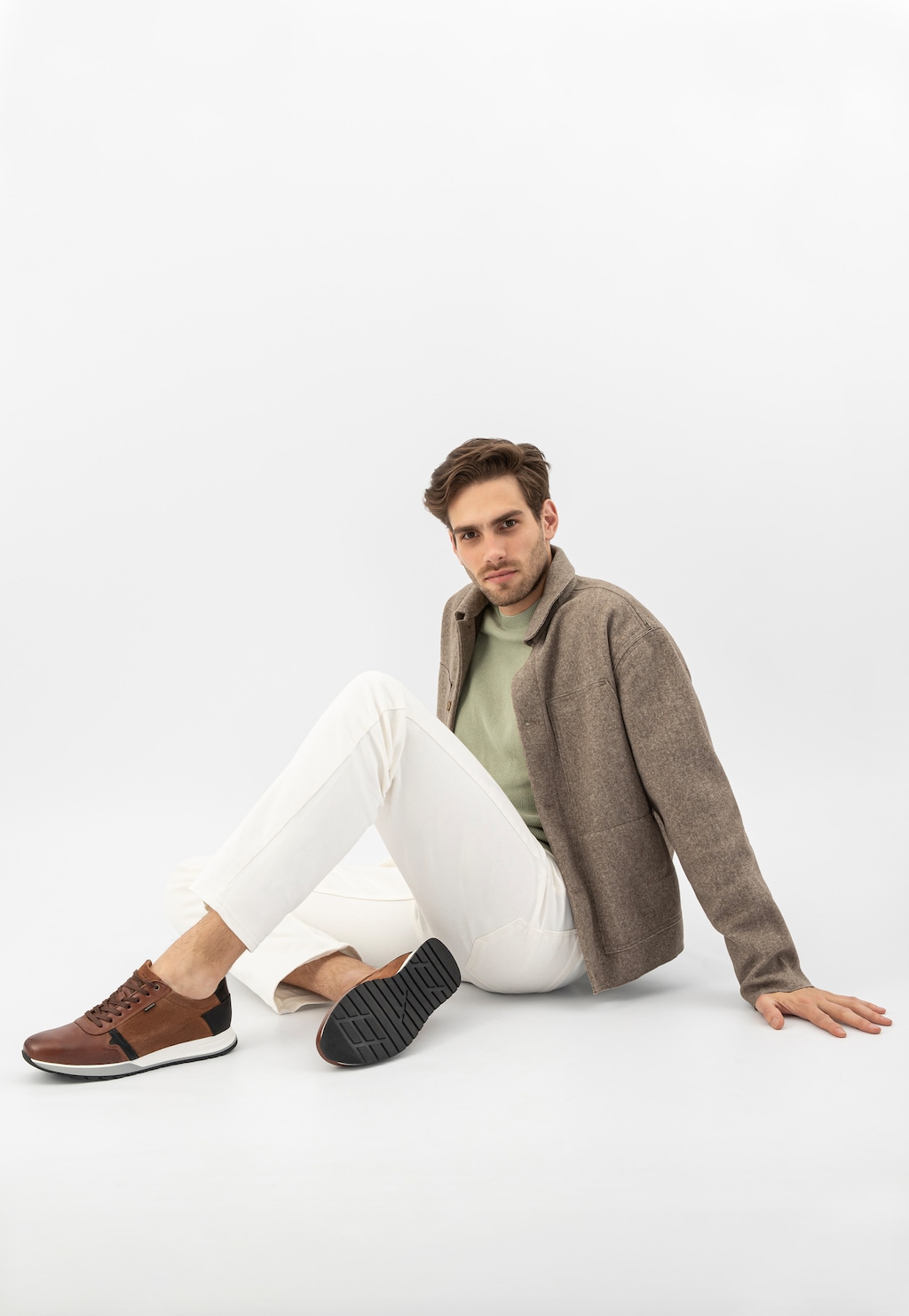 Jasnobrązowe sneakersy męskie Wojas model 10021-73 z czarnymi elementami, prezentowane na modelu w białych spodniach i brązowej marynarce.