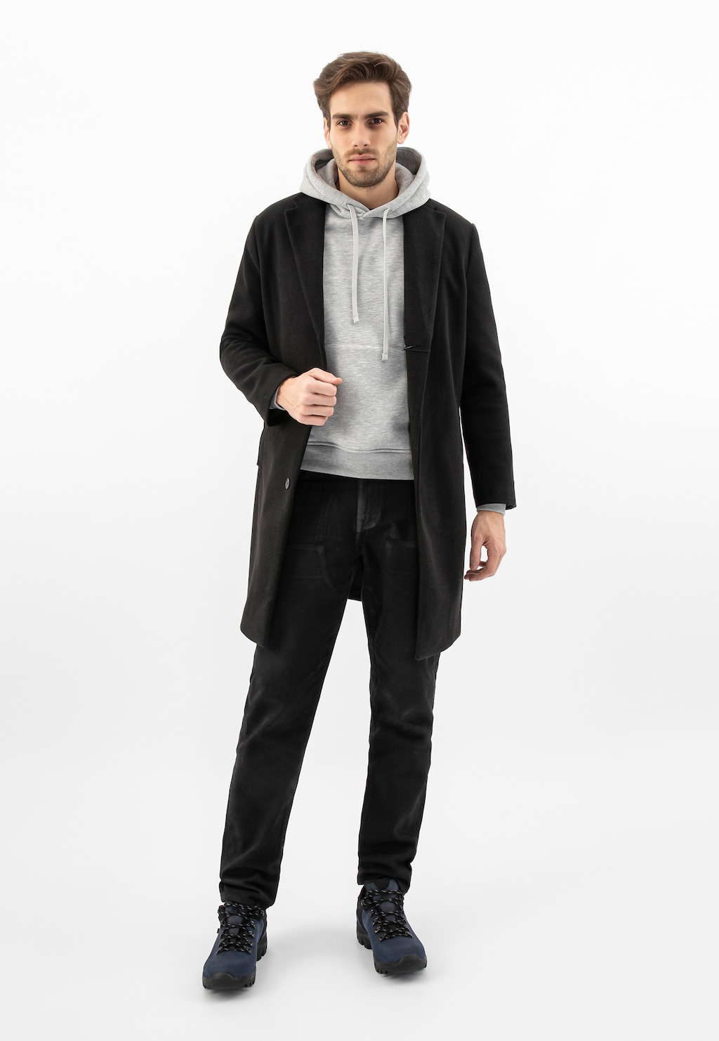 Model w stylizacji z czarnym płaszczem i szarą bluzą z kapturem, prezentujący granatowo-czarne trekkingowe buty Wojas model 9377-80 z dzianiną dystansową.