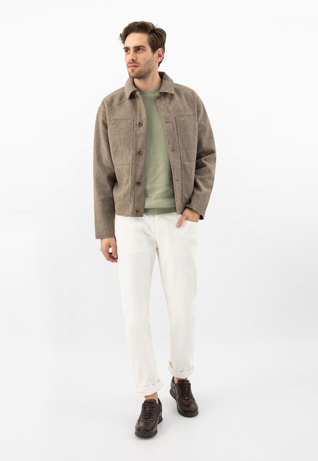 Model w stylizacji casualowej prezentujący ciemnobrązowe sneakersy Wojas 9078-52 ze skóry licowej, z beżową kurtką, zieloną bluzką i białymi spodniami.