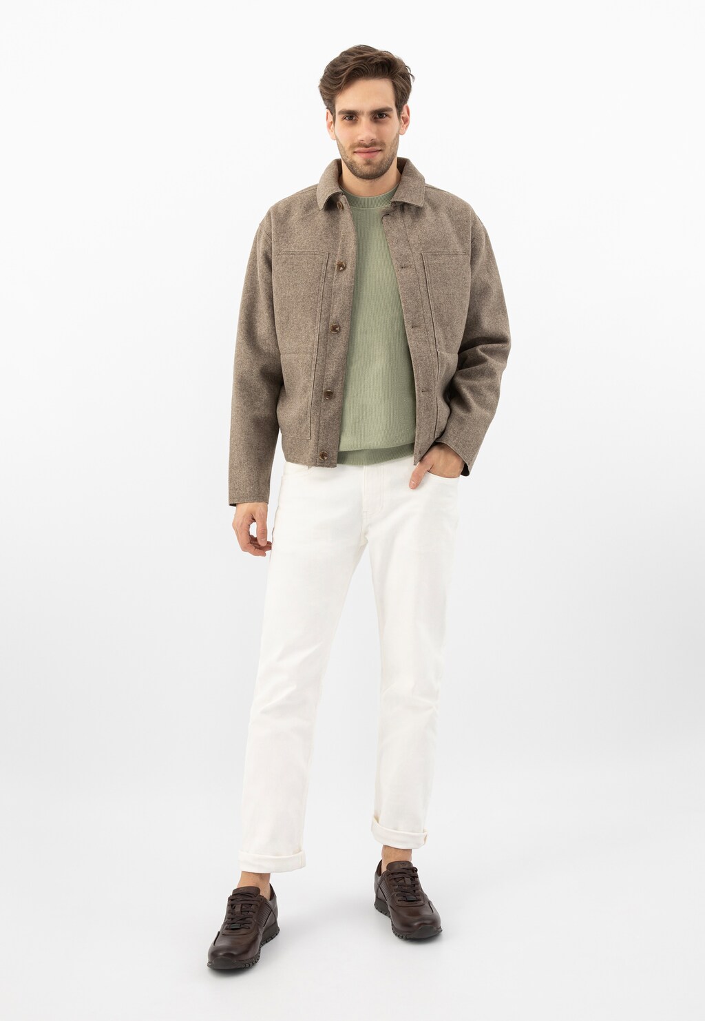 Osoba w stylizacji z ciemnobrązowymi sneakersami Wojas model 9078-52 ze skóry licowej, beżową kurtką, zieloną bluzką i białymi spodniami.