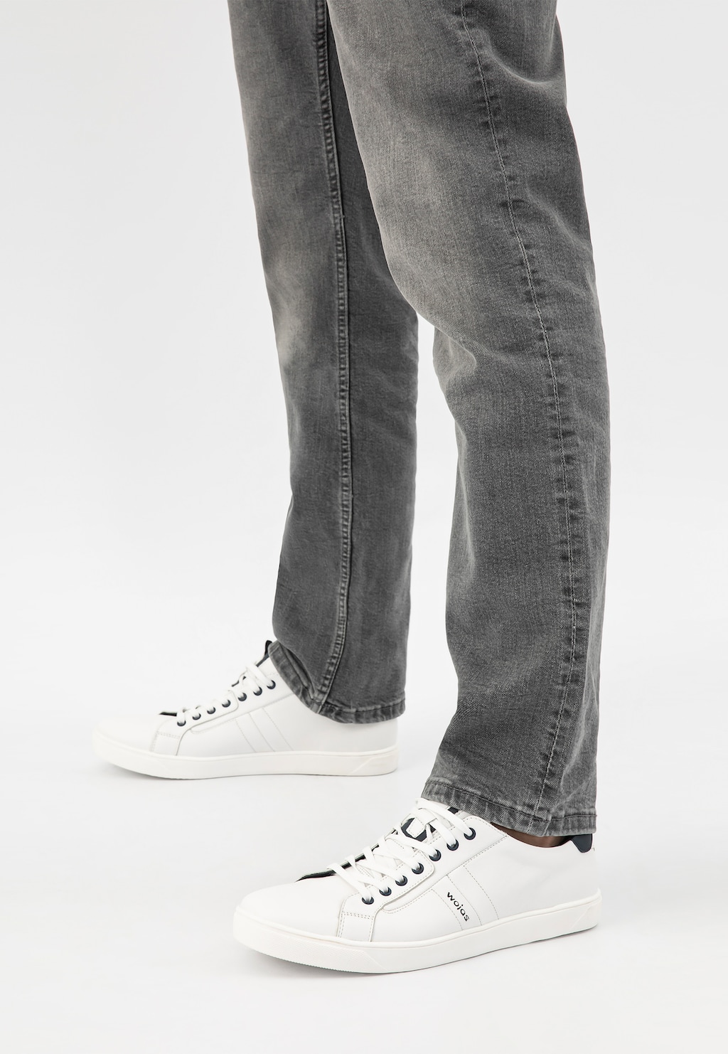 Białe skórzane półbuty męskie Wojas model 10167-57 z granatowymi wstawkami, prezentowane na nogach w szarych jeansach, widok z boku.