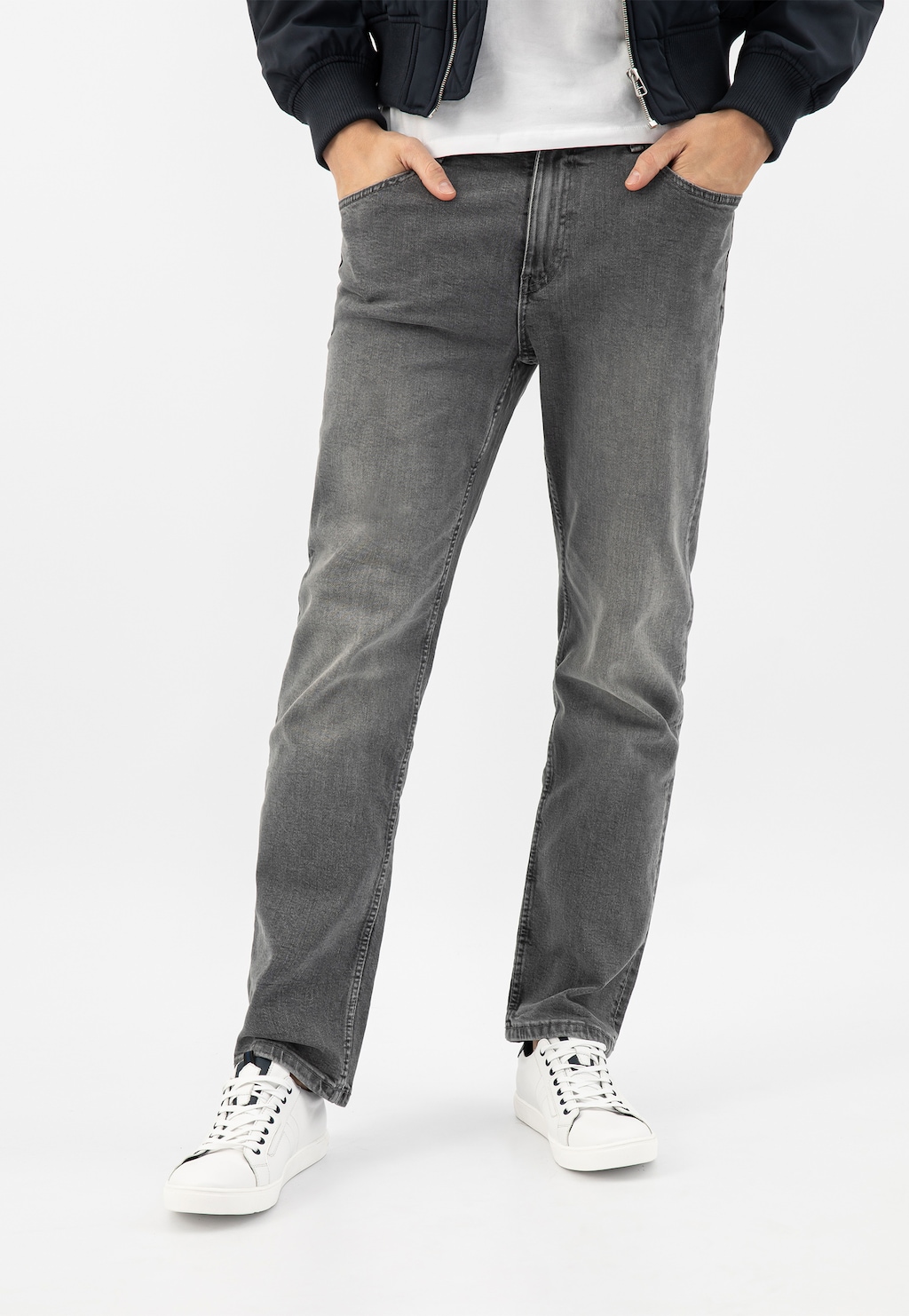 Osoba w szarych jeansach i czarnej kurtce, nosząca białe skórzane półbuty męskie Wojas model 10167-57 z granatowymi wstawkami. Ujęcie ukazuje stylową stylizację od pasa w dół.