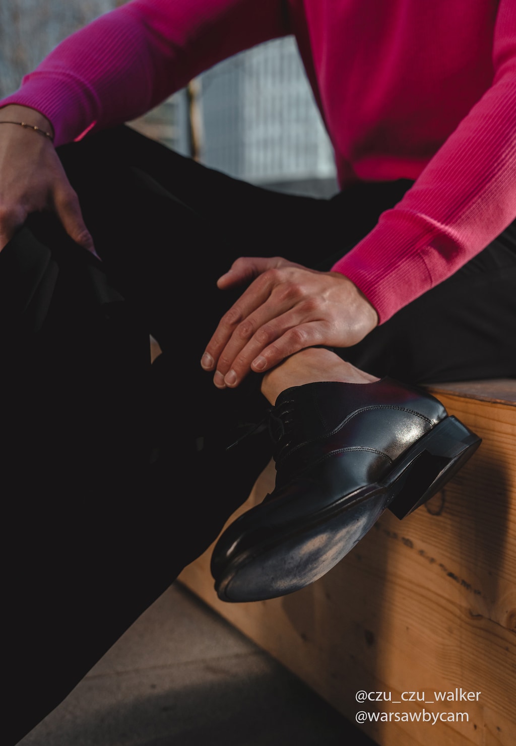 Eleganckie czarne półbuty męskie Wojas model 10058-51 z linii PREMIUM ze skórzaną podeszwą, noszone do czarnych spodni i różowego swetra, widoczne na drewnianej podłodze.
