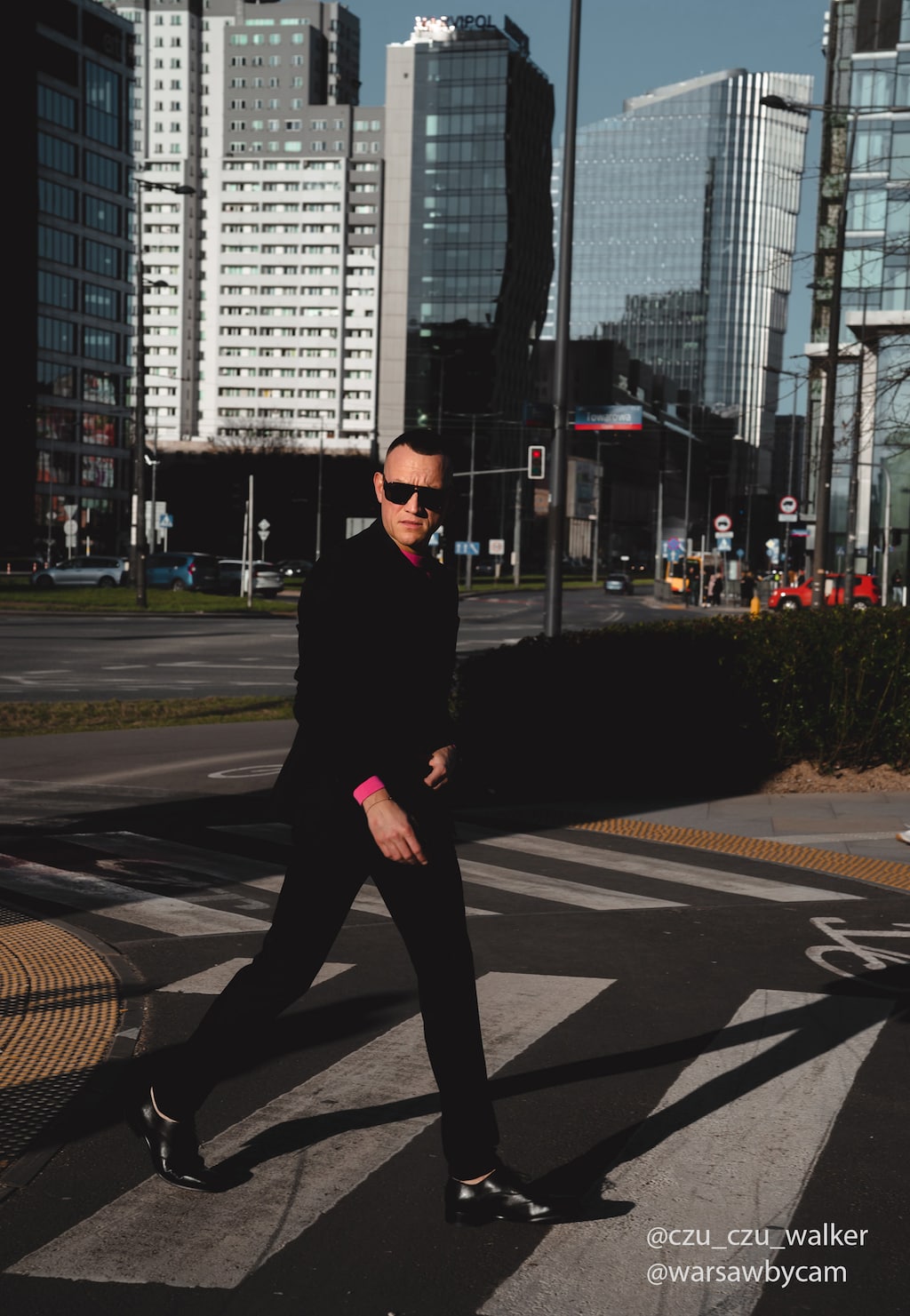 Elegancki mężczyzna w czarnym garniturze przechodzący przez ulicę w centrum miasta, prezentujący czarne wizytowe półbuty Wojas PREMIUM model 10058-51 ze skórzaną podeszwą.