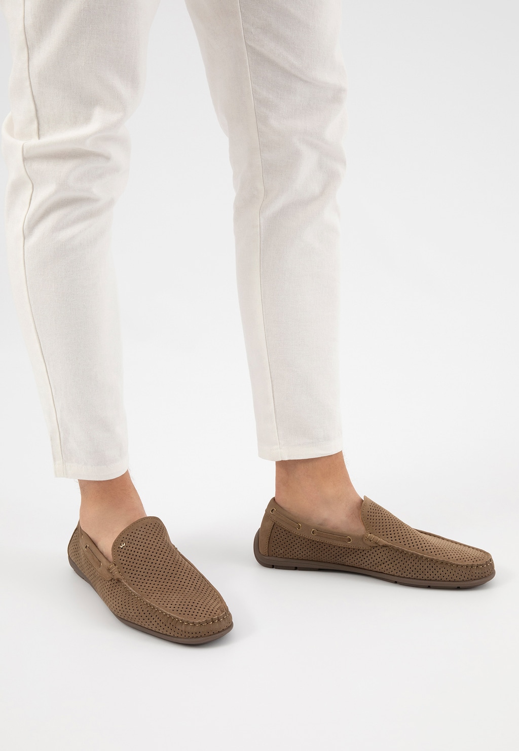 Beżowe mokasyny męskie Wojas 10103-24 z perforowaną skórą na nogach osoby w białych spodniach. Eleganckie obuwie casual o miękkim designie i przewiewnej konstrukcji.