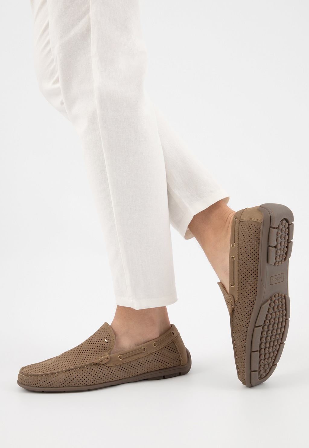 Beżowe mokasyny męskie Wojas 10103-24 z perforowaną skórą na nogach mężczyzny w białych spodniach. Widoczna podeszwa z bieżnikiem zapewniającym przyczepność.
