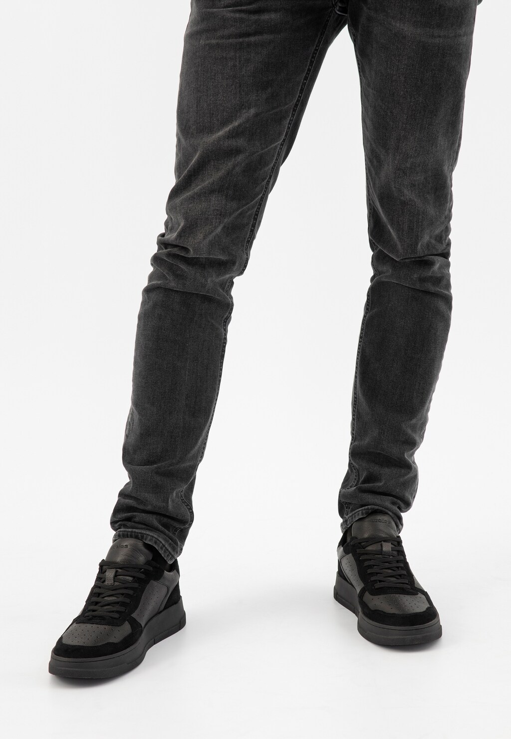 Czarne trampki męskie Wojas model 10141-71 z łączonych skór w kolorze czarno-szarym, prezentowane na nogach w ciemnych jeansach, widok z przodu.