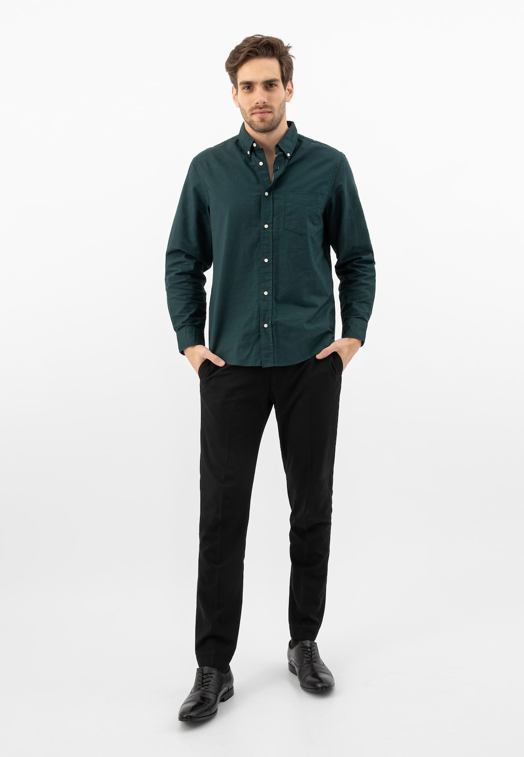 Mężczyzna w zielonej koszuli i czarnych spodniach prezentujący eleganckie czarne półbuty Wojas model 10165-51 typu quarter brogue, widok pełnej sylwetki.