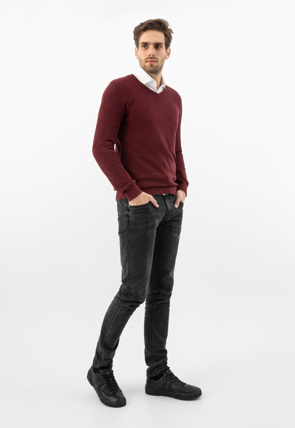 Stylowy mężczyzna w bordowym swetrze i ciemnych jeansach, prezentujący czarne skórzane trampki Wojas model 10180-51 ocieplane futerkiem, idealne na chłodniejsze dni.