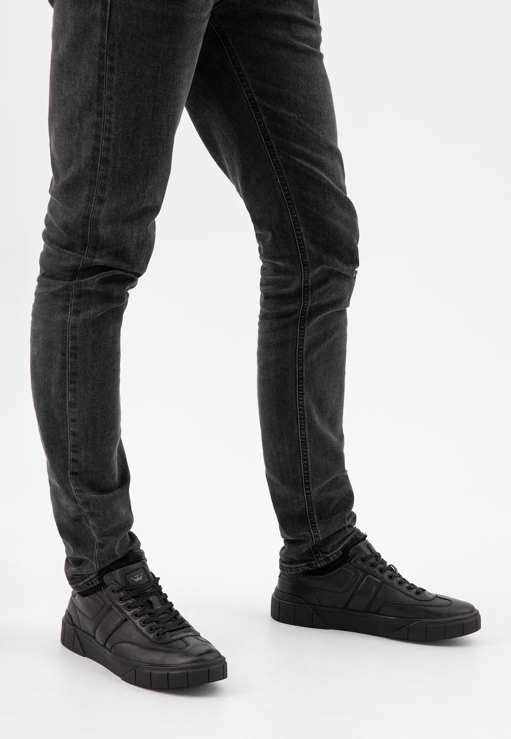 Czarne skórzane trampki męskie Wojas 10180-51 ocieplane futerkiem, prezentowane na nogach w ciemnych jeansach, widoczne z boku, podkreślające zimowy, sportowy styl.