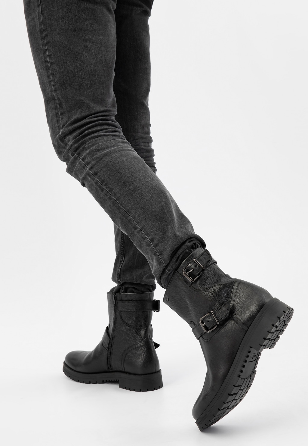 Czarne męskie bikery Wojas 20022-51 ze skóry licowej z klamrami, noszone z ciemnymi jeansami. Widok z tyłu pokazuje charakterystyczną podeszwę i zapięcia.