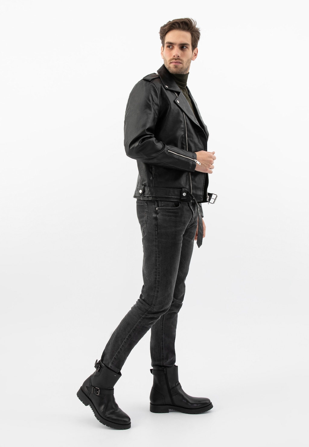 Model w całkowicie czarnej stylizacji prezentuje czarne męskie bikery Wojas 20022-51 ze skóry licowej, zestawione z kurtką motocyklową i obcisłymi jeansami.