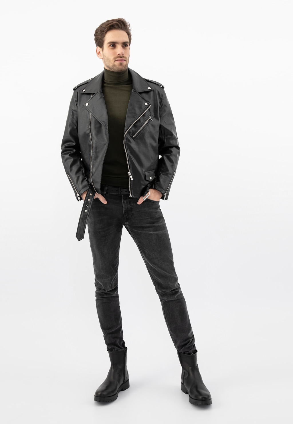 Model w czarnej skórzanej kurtce i ciemnych jeansach prezentuje czarne męskie botki Wojas model 20028-51 z zamkiem. Stylowa kompozycja na neutralnym tle.