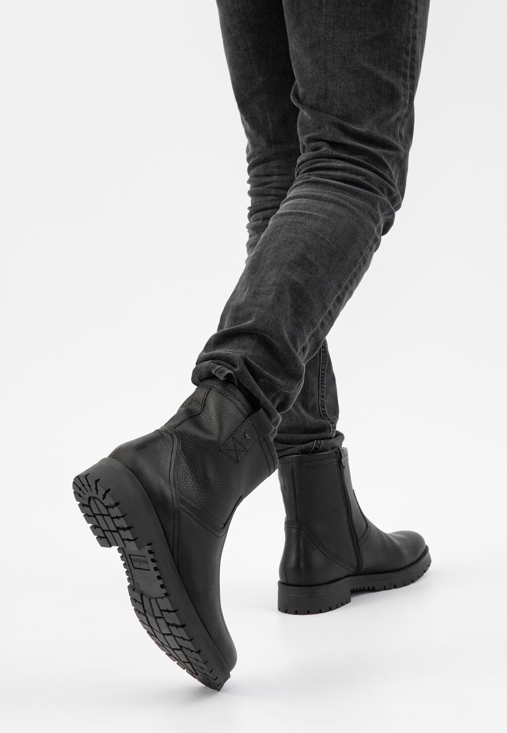 Eleganckie czarne męskie botki Wojas model 20028-51 z zamkiem, widoczne na nogach w ciemnych dżinsach. Podeszwa o wyraźnym bieżniku zapewnia stabilność i przyczepność.