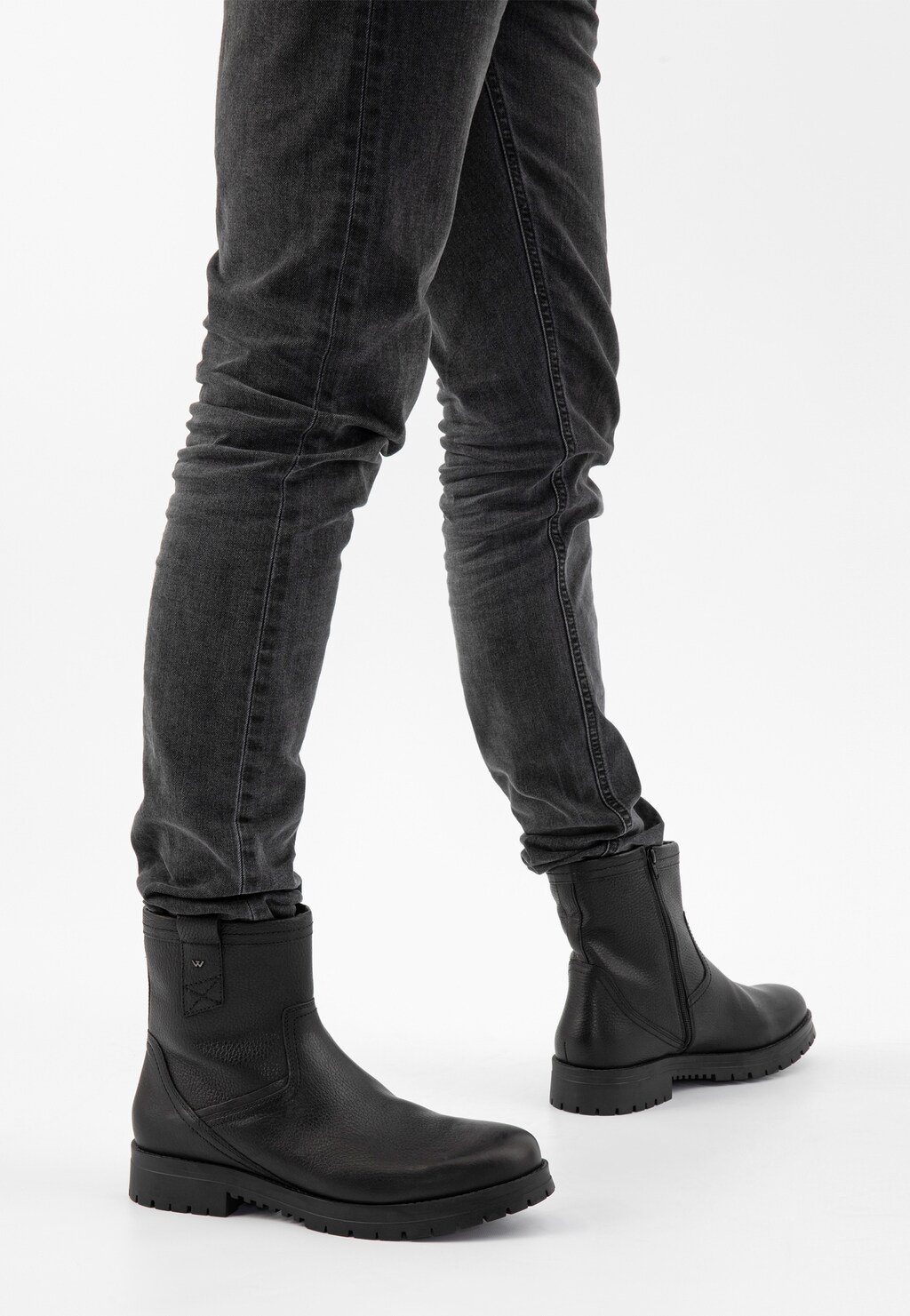 Czarne męskie botki Wojas model 20028-51 z bocznym zamkiem zaprezentowane na nogach w ciemnych jeansach. Widok z perspektywy bocznej, ukazujący mocną podeszwę i elegancki profil.