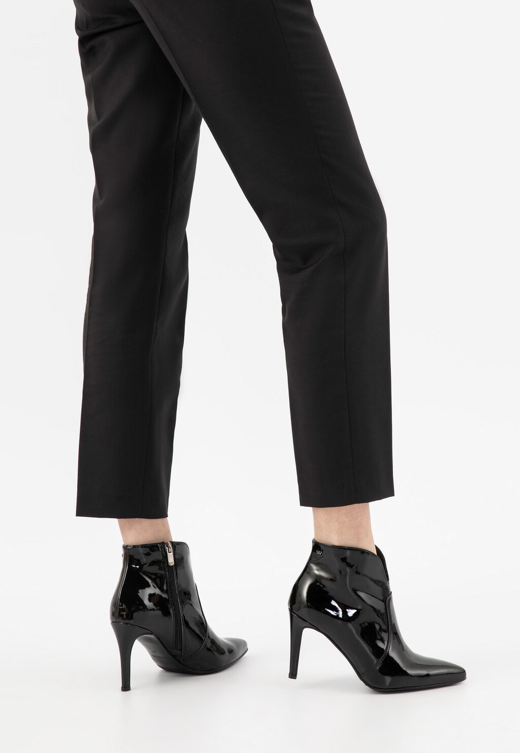 Eleganckie czarne lakierowane botki Wojas model 55096-31 prezentowane na nogach modelki w eleganckich spodniach, widok od tyłu, podkreślając smukły obcas i stylowy profil.
