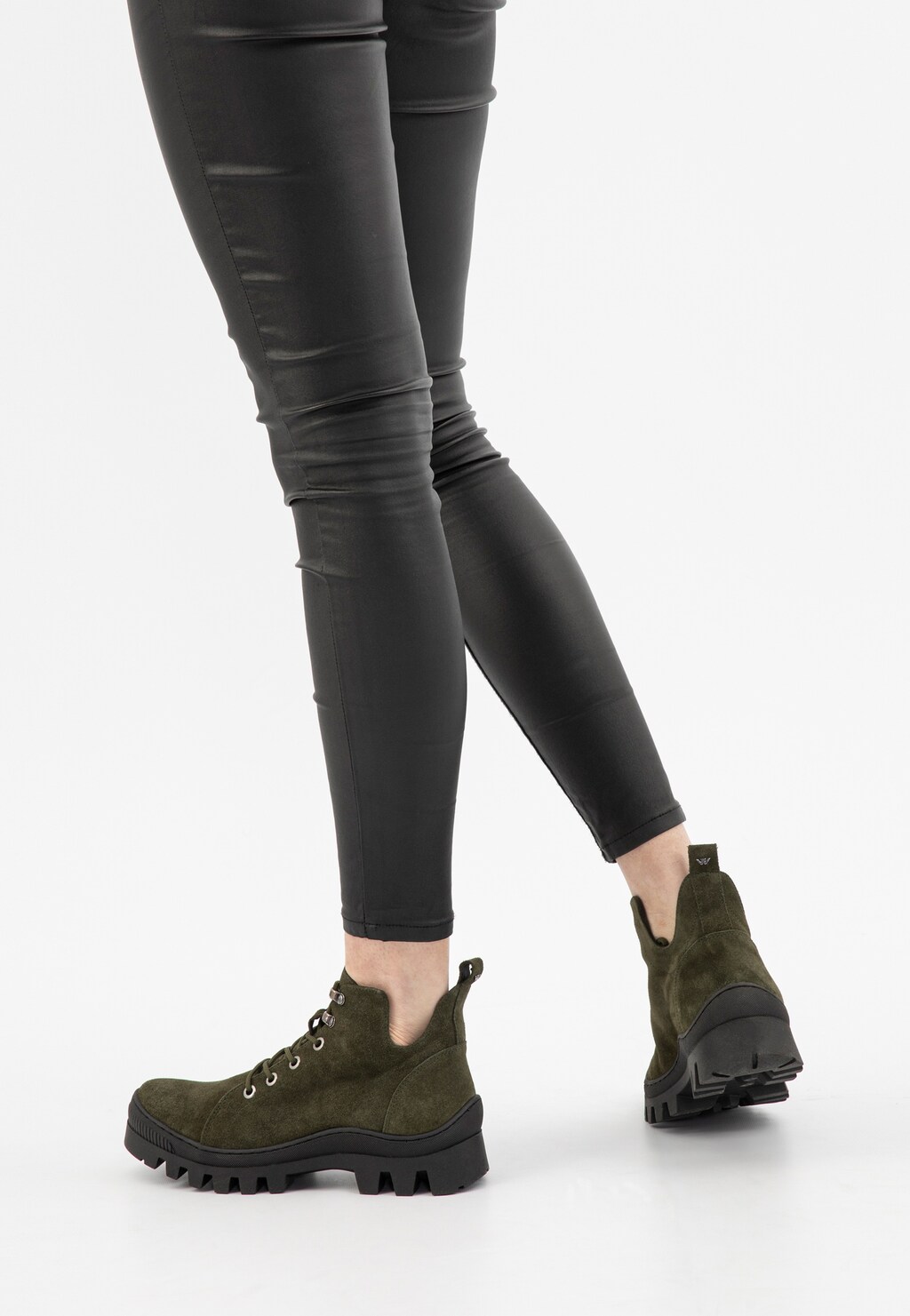 Nogi modelki w czarnych obcisłych spodniach prezentujące zielone trzewiki damskie Wojas model 64073-67 z masywną podeszwą i sznurowaniem, widok z tyłu.