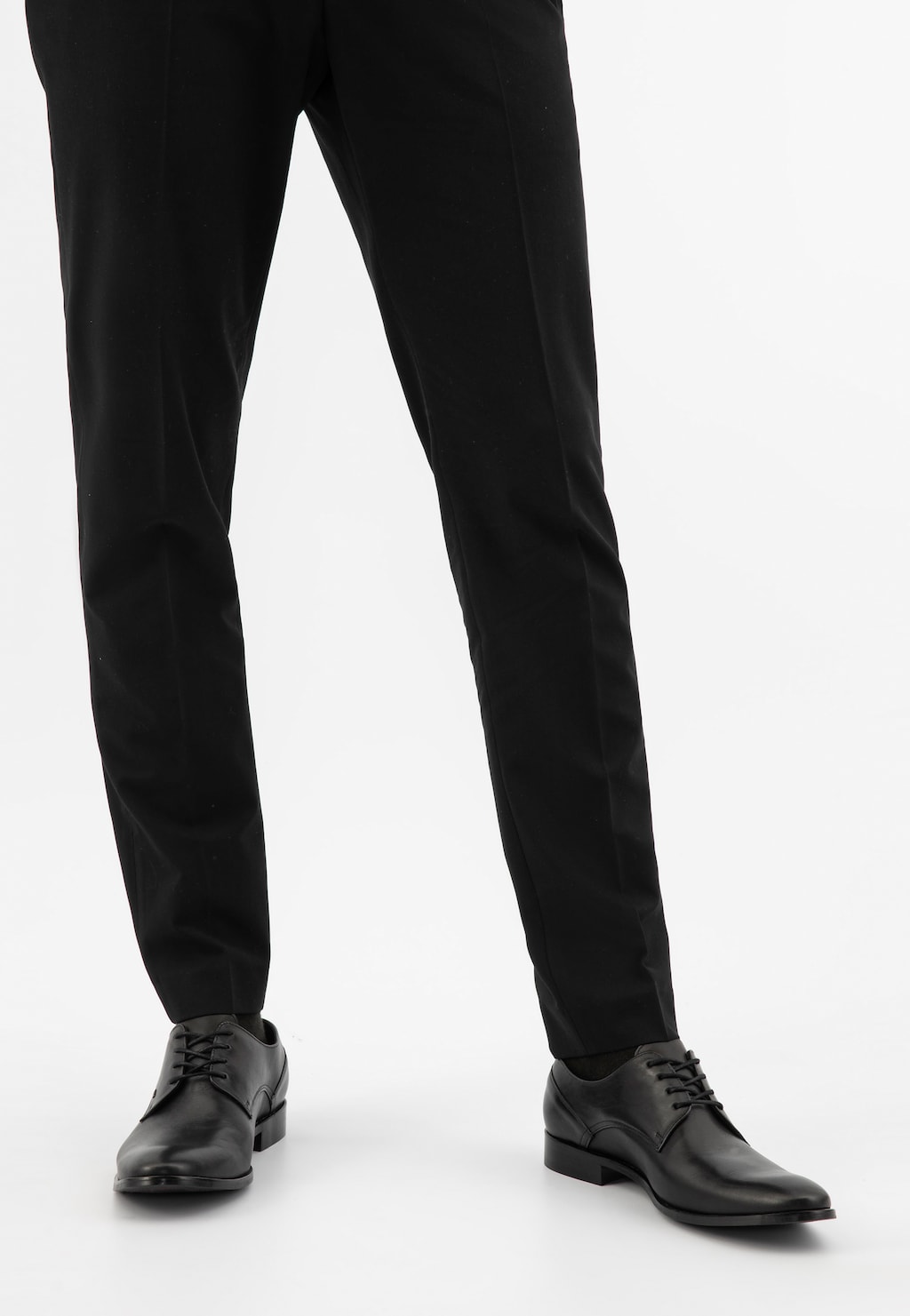 Eleganckie czarne wizytowe półbuty męskie Wojas model 7030-51 noszone z czarnymi spodniami garnituru. Stylowe buty ze sznurówkami widoczne z przodu.