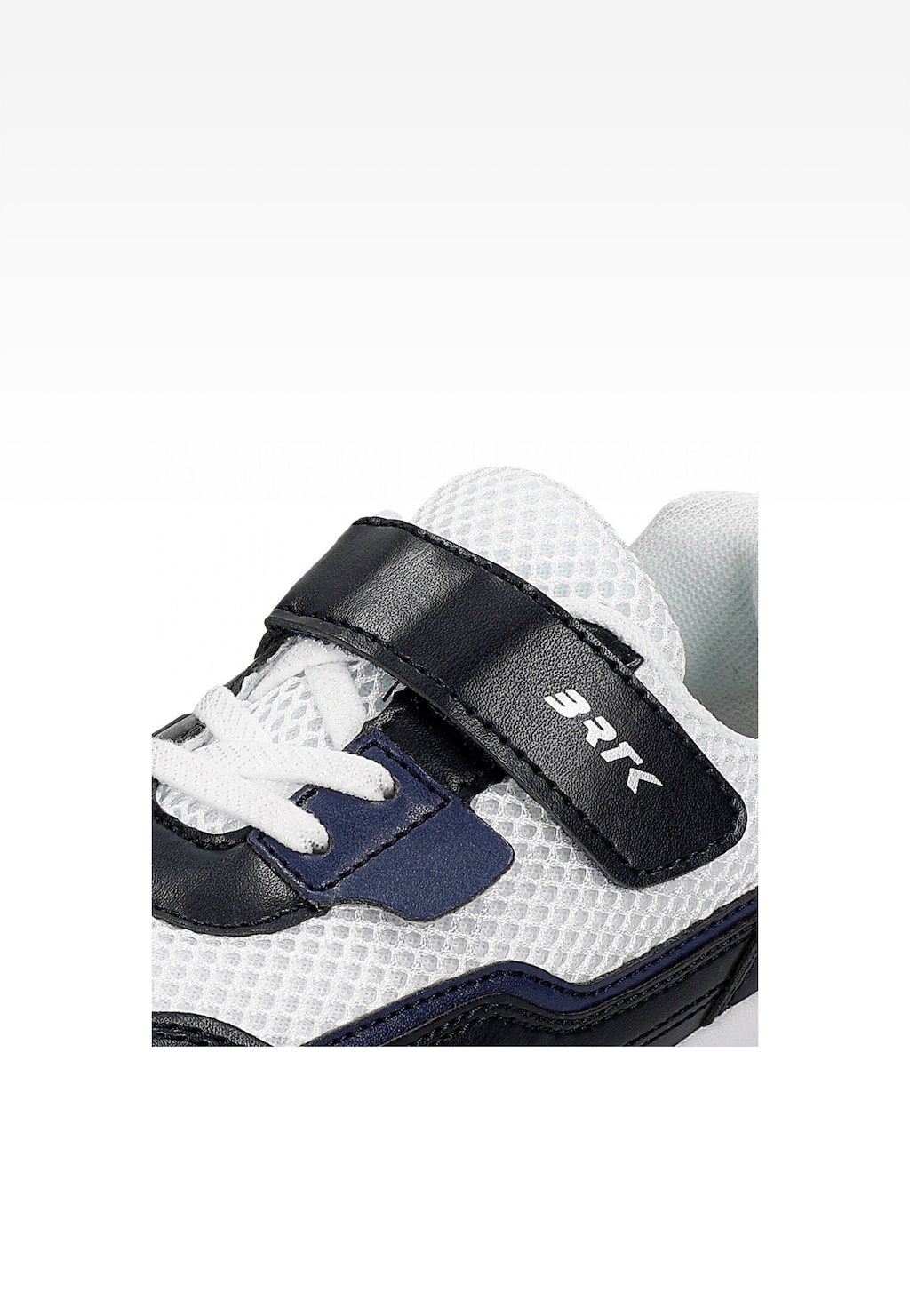 Granatowo-białe półbuty dziecięce Bartek 15042402 z rzepem i sznurowadłami. Zbliżenie na górną część buta z widocznym logo RTK na rzepie.