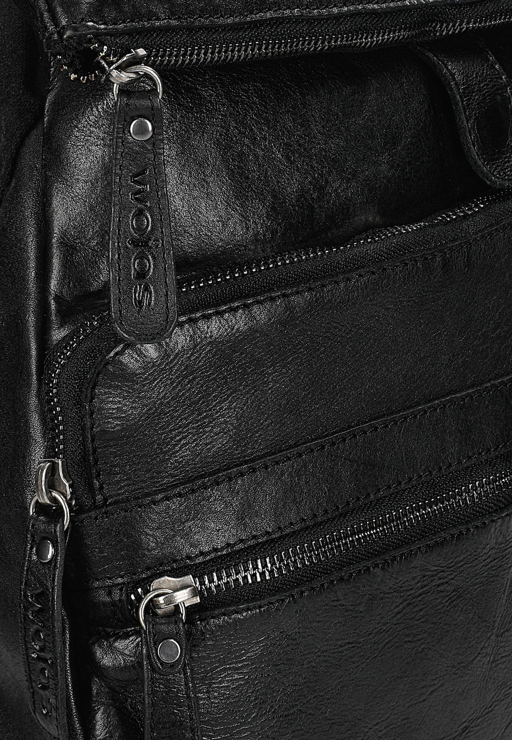 Zbliżenie na czarny plecak Wojas model 80080-51 wykonany z licowej skóry. Widoczne metalowe suwaki i skórzana zawieszka z logo marki. Praktyczne kieszenie zewnętrzne z zamkami błyskawicznymi.