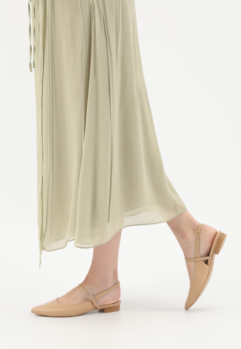 Beżowe baleriny Wojas model 44046-54 z odkrytą piętą na niskim obcasie, prezentowane na nodze kobiety w zwiewnej, jasnej spódnicy, idealne do eleganckich stylizacji.